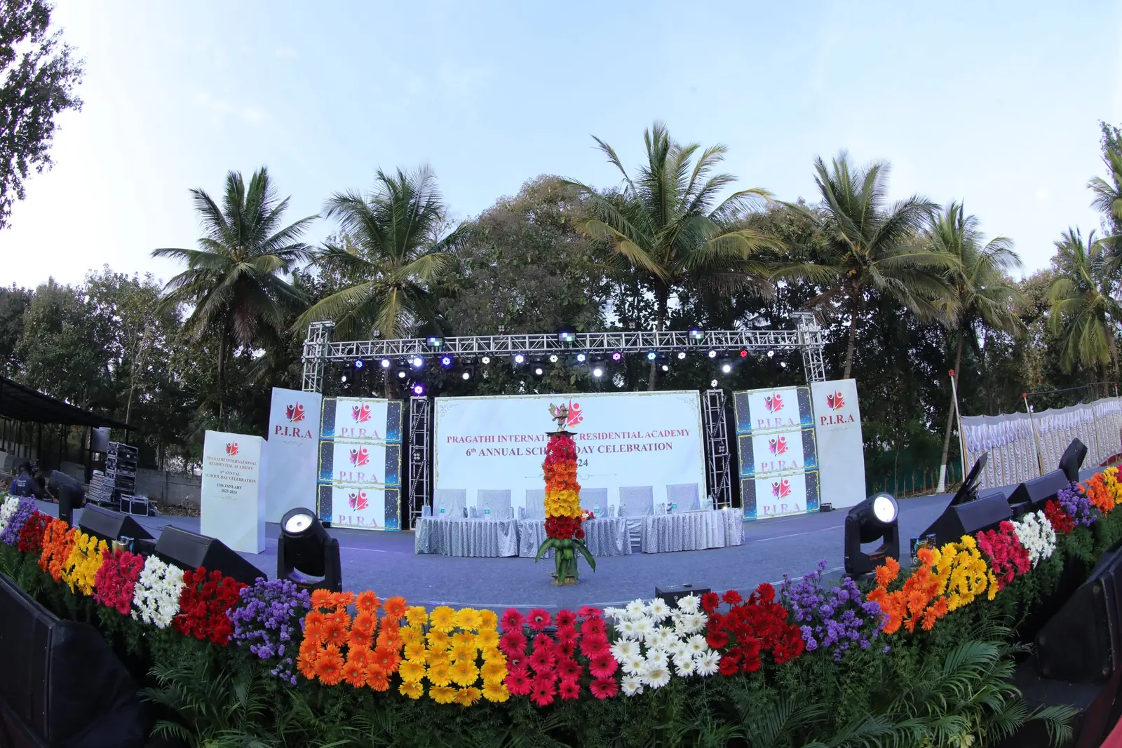 PIRA annual day stage lit at dusk with flower-lined edge